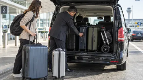 Autista controlla valigie e passeggino piegato nel veicolo aeroportuale