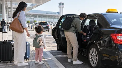 Famille vérifiant un siège enfant dans un taxi à l’aéroport